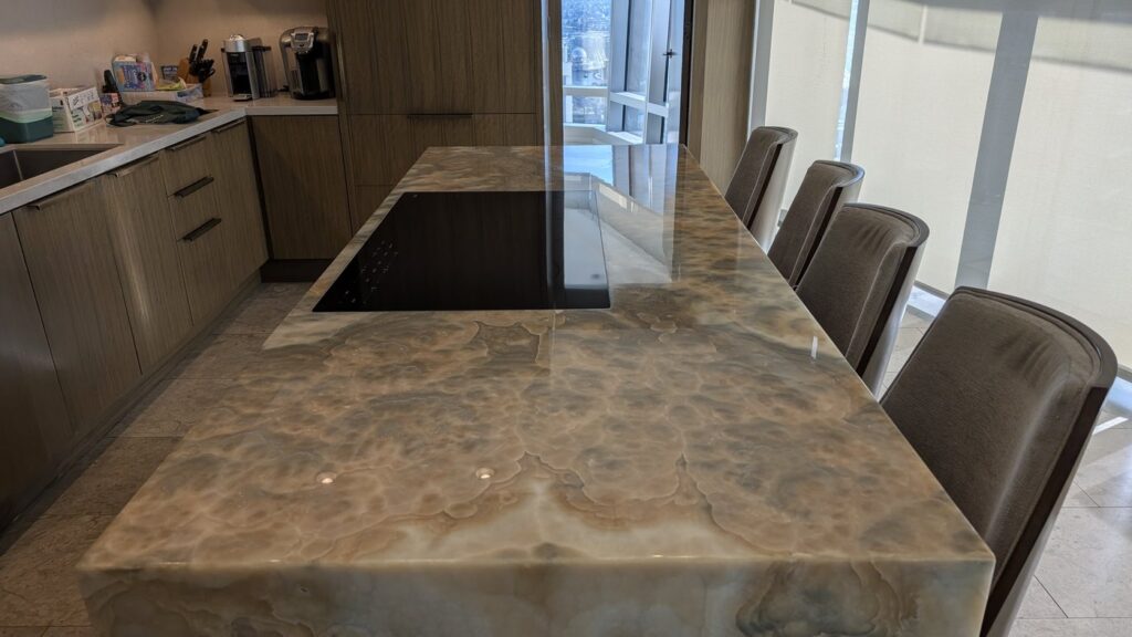 The same onyx island after polishing, the chairs and the window reflected in the mirror finish