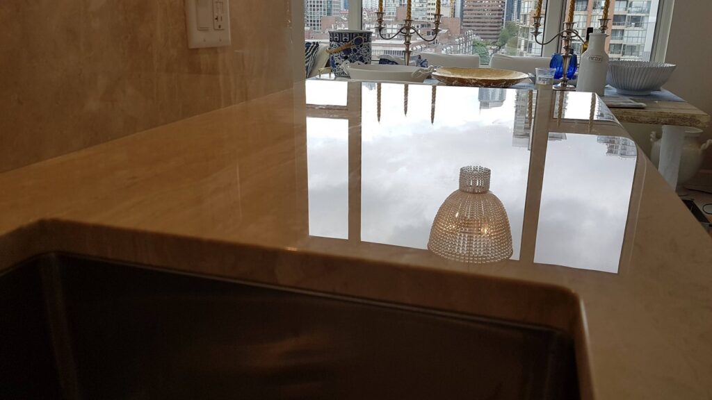 The same Yaletown marble counter after etch removal, polished and reflecting the skyline through the window