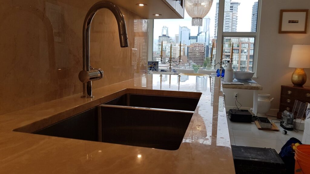Cream marble kitchen counter beside the sink in a Yaletown condo, dulled by etch marks, before restoration