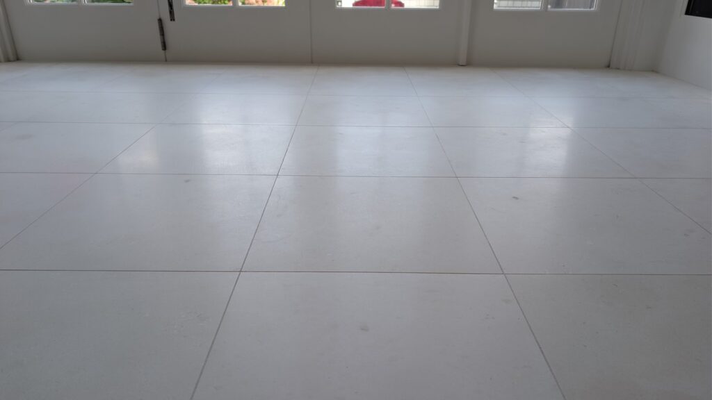 The same open room after restoration, the limestone tiles clean and pale, French doors across the far wall