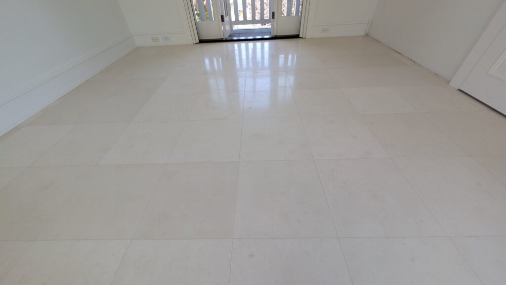 Close view of large pale limestone tiles with a satin finish, the window light spread softly across them