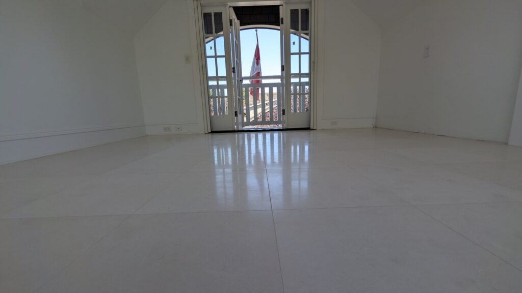 Pale limestone floor in a Point Grey home finished satin, the French doors and the light reflected softly in the stone