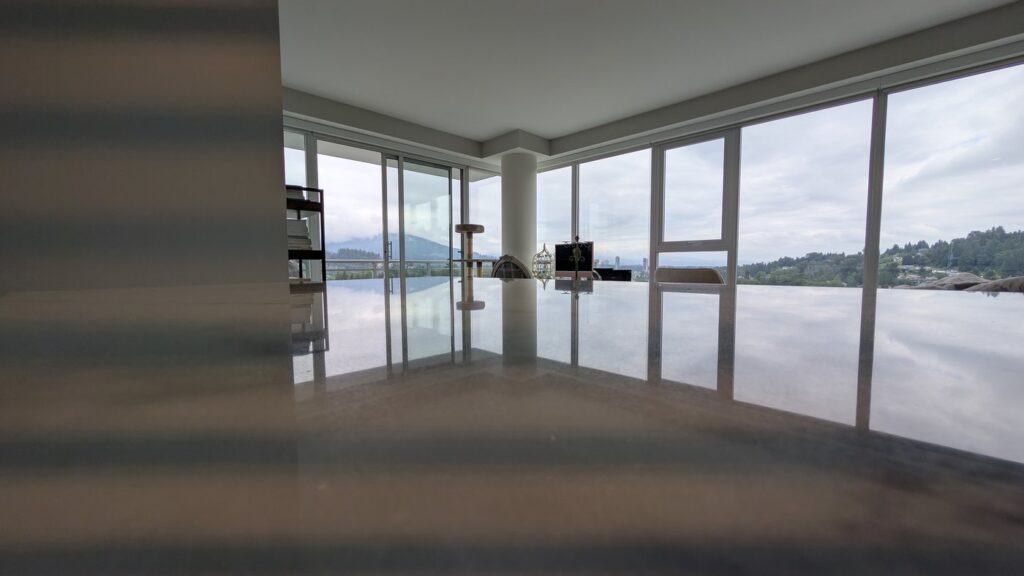 The same Port Moody marble island after honing and polishing, with the windows and the view reflected in the top