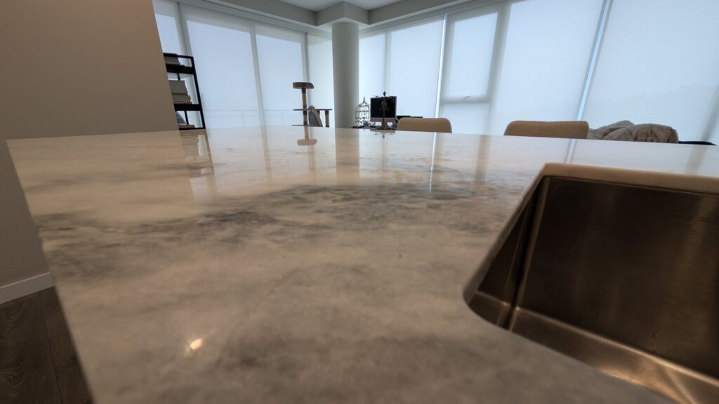 Marble kitchen island top in a Port Moody home, blotchy and dull around the sink, before restoration