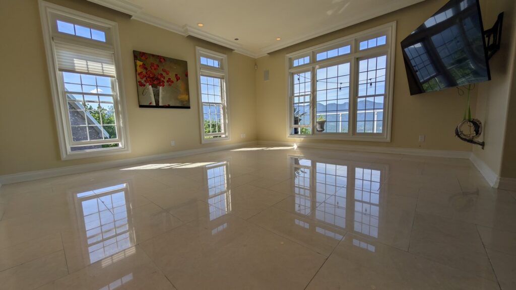The same West Vancouver sitting room floor after honing and polishing, the windows reflected across the marble