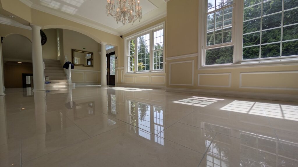 The same West Vancouver hall floor after restoration, the columns and windows reflected in the marble