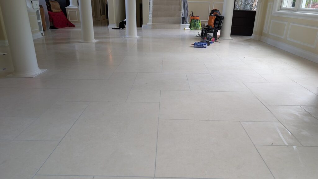 Marble hall floor between columns in a West Vancouver home, dull and scuffed, before restoration