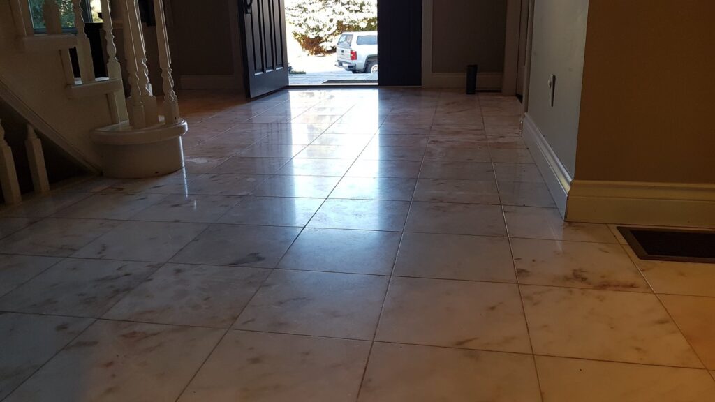 Cream marble entry hall floor with rust-toned veining, dull and worn, before restoration