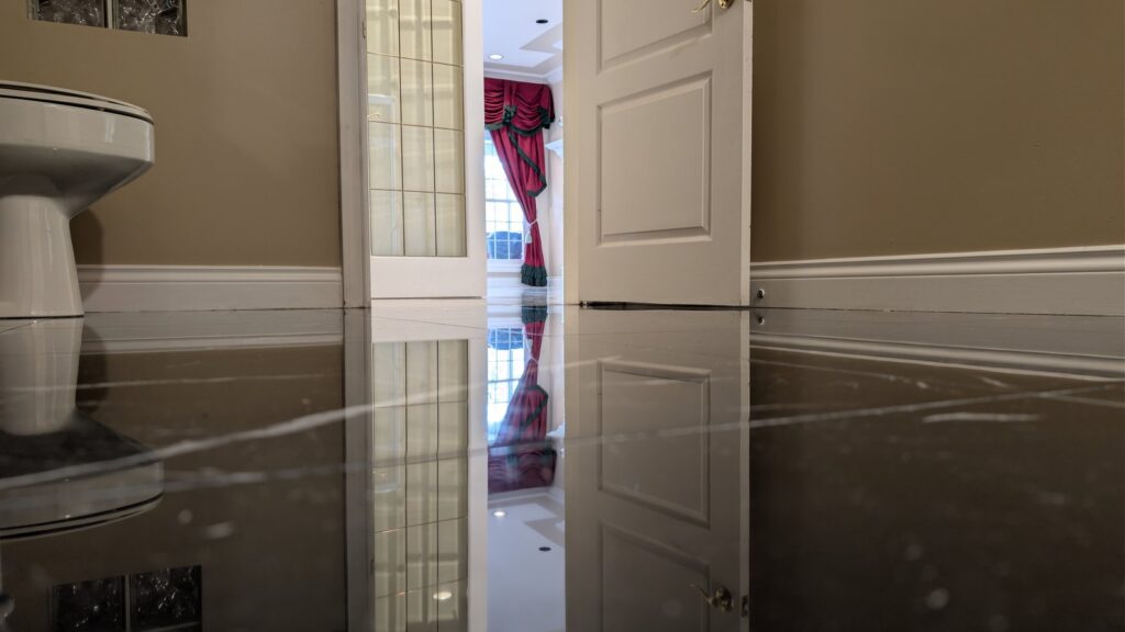 Black marble floor with white veining in a West Vancouver home after restoration, the doorway reflected in the polish