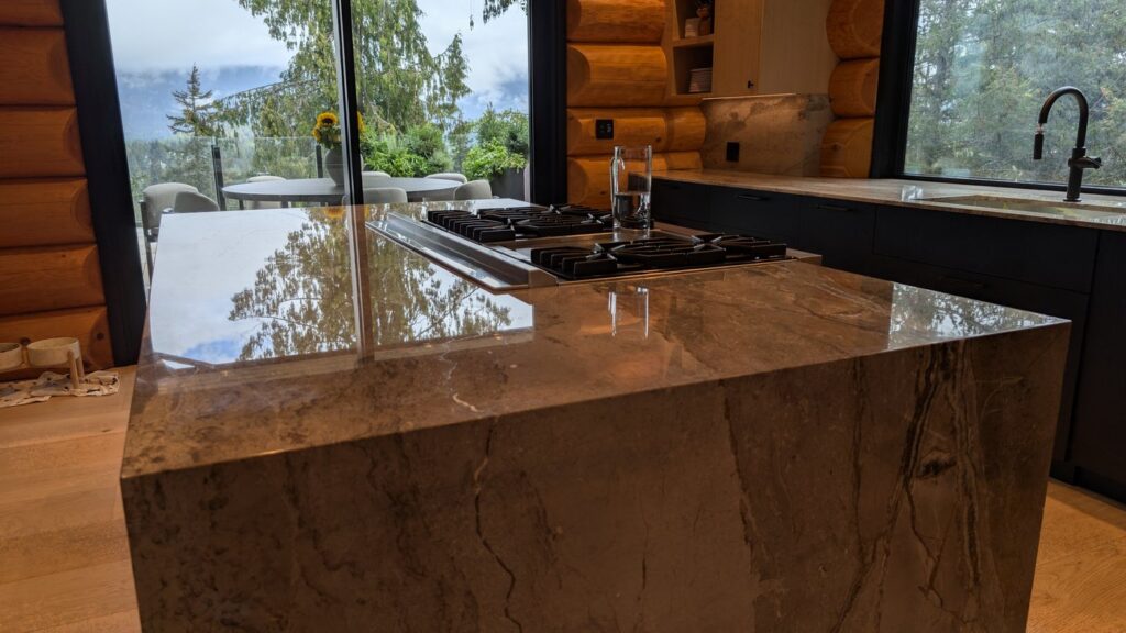 The same Whistler marble island after polishing, the window and the log wall reflected in the top