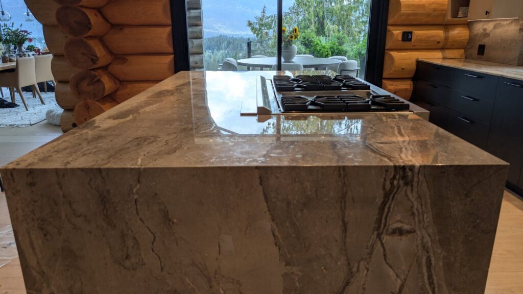 Marble kitchen island with a cooktop in a Whistler log home, the top dull and worn, before polishing