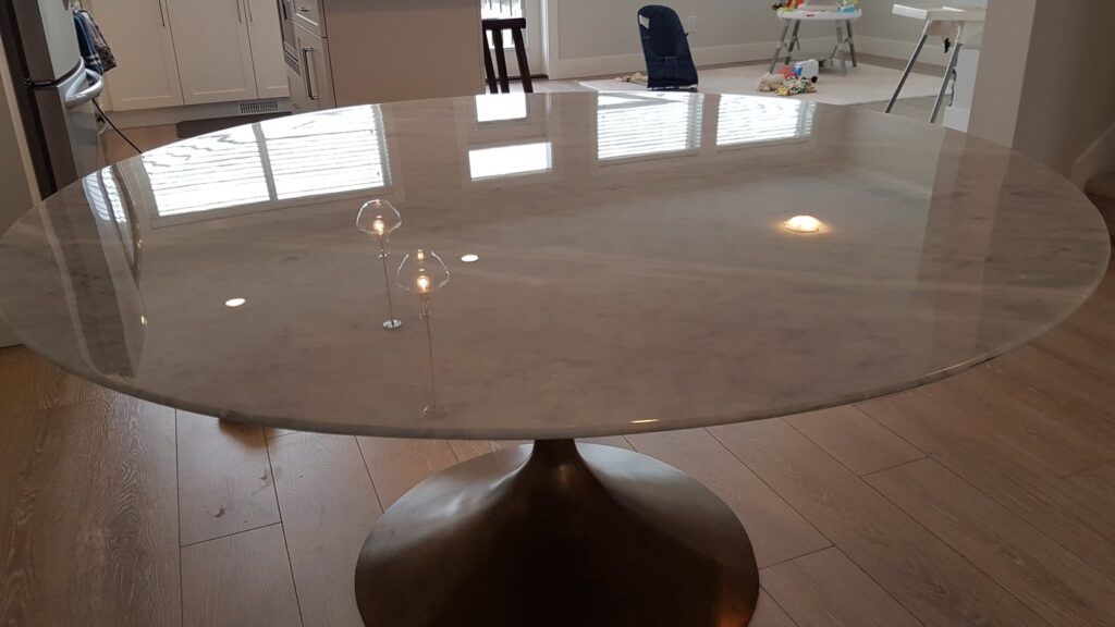 The same round marble table after polishing, the window reflected in the top