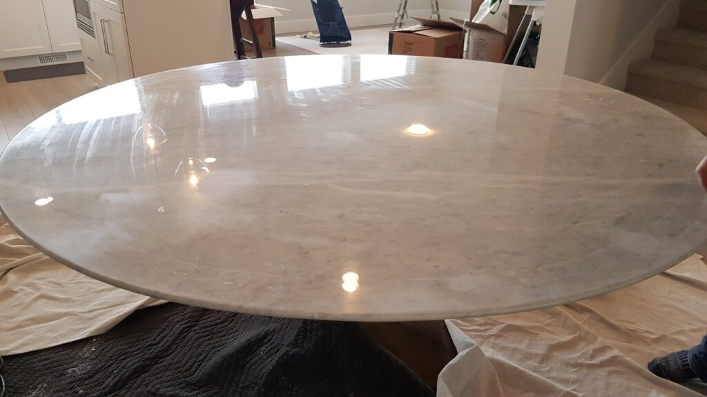 Round pale marble dining table, dull with a flat finish, before polishing