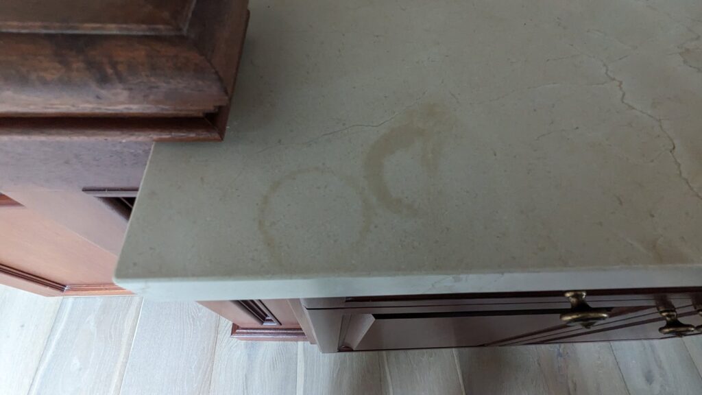 Overlapping ring stains discolouring a pale marble vanity top, before stain removal