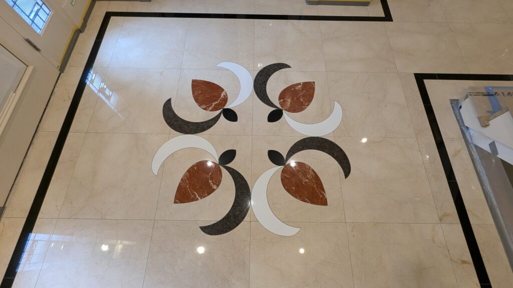The same Kitsilano entry floor after restoration, the medallion and border polished and the windows reflected in the marble