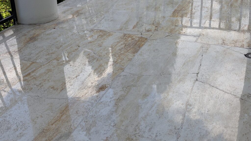 Travertine terrace floor in a Point Grey home after restoration, polished and reflecting the columns and trees